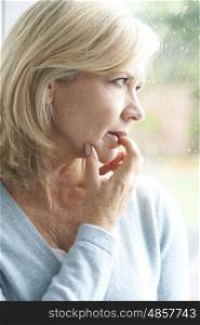 Sad Mature Woman Suffering From Agoraphobia Looking Out Of Window