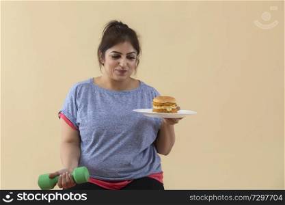 sad Overweight Woman holding a burger and dumbbell