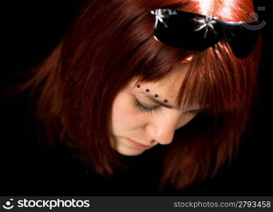 Sad redhead girl looking down and feeling lost. Shot in studio.