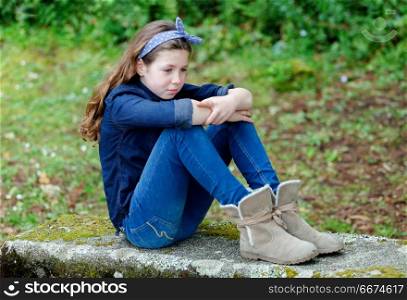 Sad small girl with ten years old sitting on a bench. Sad small girl with ten years old wearing a blue hair scarf sitting on a bench