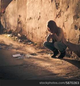 Sad teenage girl crying in the dirty poor ghetto. Sad teenage girl