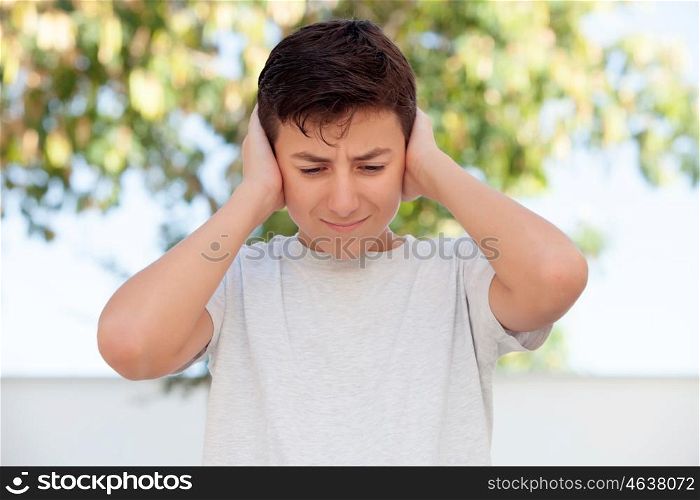 Sad teenager boy outdoor covering his ears