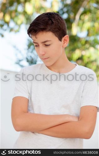 Sad teenager boy with crossed arms looking down outdoor