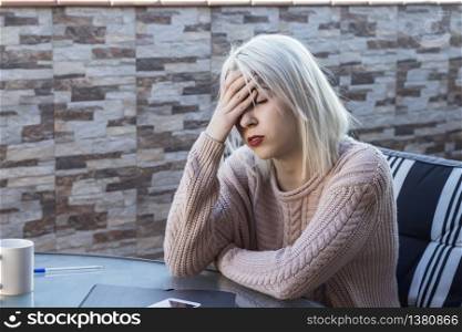 Sad, unhappy woman sitting on terrace at home