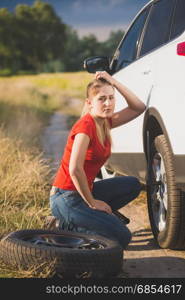 Sad woman got confused about changing flat tire in the field