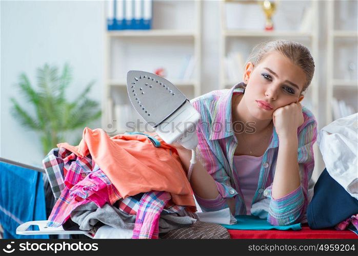 Sad woman ironing clothing at home