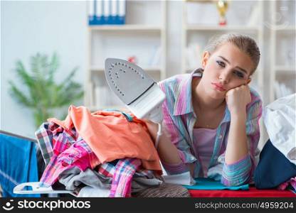 Sad woman ironing clothing at home