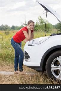Sad woman looking at broken car and waiting for help on the rural road