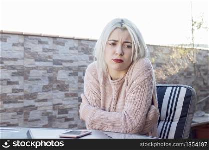 Sad woman sitting on a chair in a terrace arms crossed