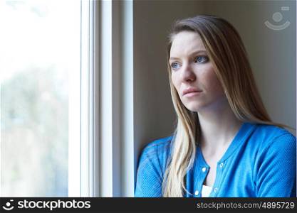 Sad Woman Suffering From Depression Looking Out Of Window