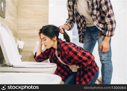 Sad woman throwing up in the toilet, hangover after house party. Drunk female person with headache in bathroom