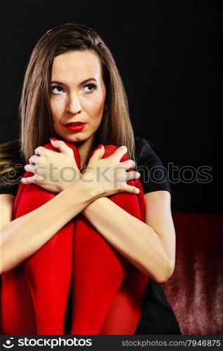Sad woman vivid color pantyhose sitting on couch black background