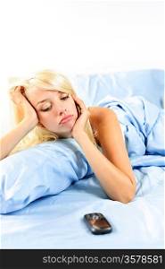 Sad woman waiting by phone in bed