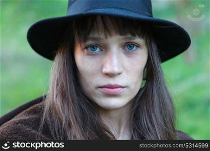 Sad woman with black hat in the countryside