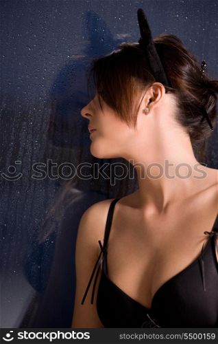 sad woman with cat ears at the rainy window