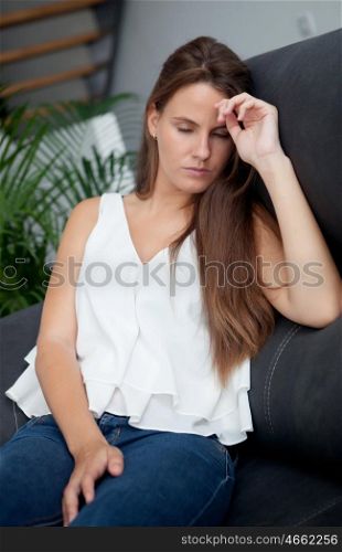Sad woman with eyes closed sitting alone in her couch home