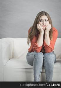 Sad worried woman waiting of something sitting on sofa being very nervous and stressed.. Worried woman sitting on sofa