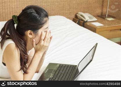 sad young asian woman working with laptop in bedroom