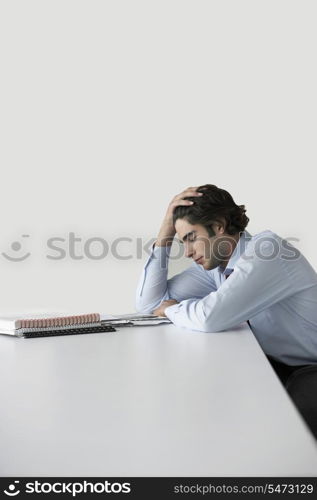 Sad young businessman leaning on desk in office