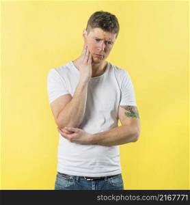 sad young man having toothache against yellow background