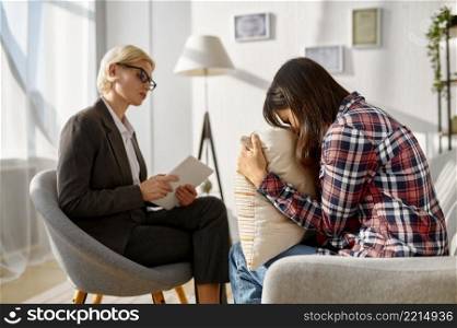 Sad young woman crying to the pillow emotionally talking about problem to psychologist. Woman crying crumpling napkins talking to psychologist