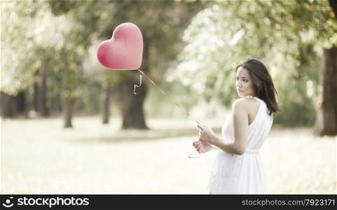 Sad Young Woman Standing with a Red Shaped Heart Balloon Outdoors