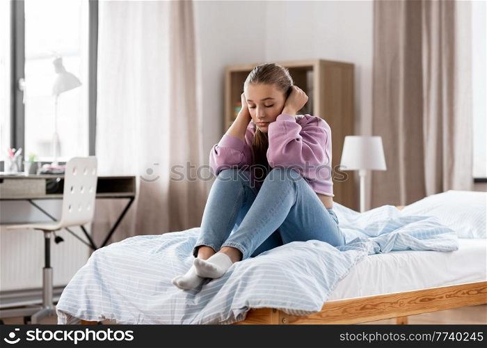sadness and people concept - sad girl sitting on bed at home. sad girl sitting on bed at home
