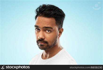 sadness and people concept - sad young indian man over blue background. sad young indian man over blue background