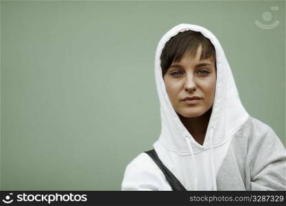 sadness in her eyes, young woman with white hood on urban wall background