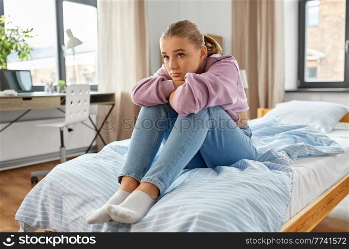 sadness, mental health and people concept - sad girl sitting on bed at home. sad girl sitting on bed at home