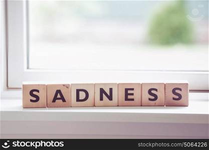 Sadness word made of wood in a bright window
