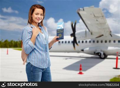 safe travel, tourism and health care concept - happy smiling young woman with air ticket and immunity passport over airport background. happy woman with air ticket and immunity passport