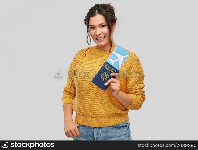 safe travel, tourism and health care concept - happy smiling young woman with air ticket and immunity passport over grey background. happy woman with air ticket and immunity passport