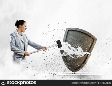 Safety concept. Image of businesswoman crashing shield with hammer
