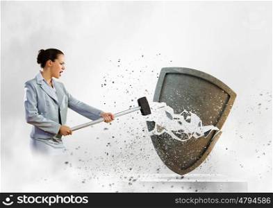 Safety concept. Image of businesswoman crashing shield with hammer