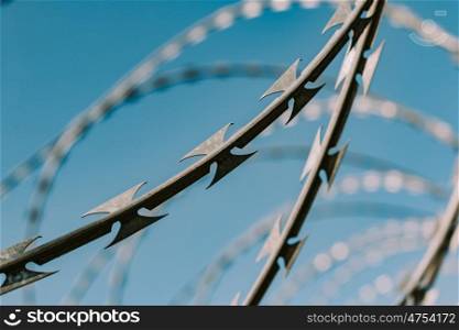 Safety fence of barbed wire against the blue sky