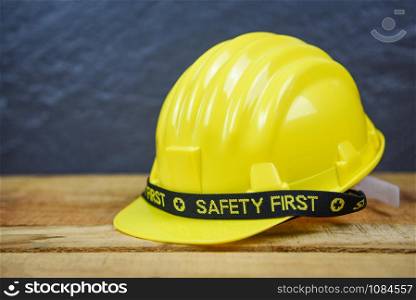 Safety first concept yellow hard safety wear helmet hat / Engineer worker helmet on wooden background