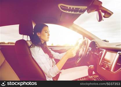 safety, road trip, technology, travel and people concept - woman driving car with smarhphone. woman driving car with smarhphone