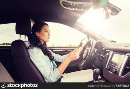 safety, road trip, technology, travel and people concept - woman driving car with smarhphone. woman driving car with smarhphone