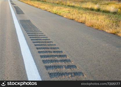 safety rumble strips on a highway shoulder to reduce run-off-road collisions, driving safety concept