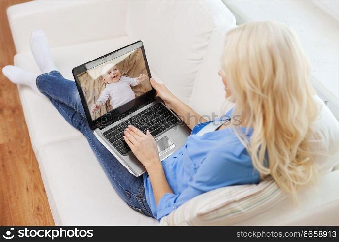 safety, technology and family concept - mother watching her baby by video monitor on laptop computer at home. mother watching baby by video monitor on laptop