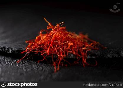 Saffron dry petals spices heap on black slate stone table