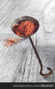 saffron in old spoon on wooden backgound. saffron in spoon on wooden backgound