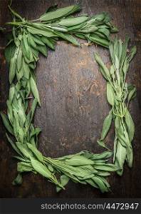 Sage leaves on dark wooden background, frame, top view