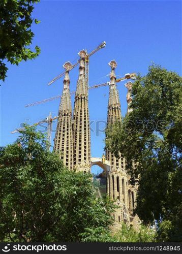 Sagrada familia church behind trees by beautiful day in Barcelona, Spain. Sagrada familia church in Barcelona, Spain