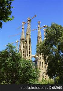 Sagrada familia church behind trees by beautiful day in Barcelona, Spain. Sagrada familia church in Barcelona, Spain