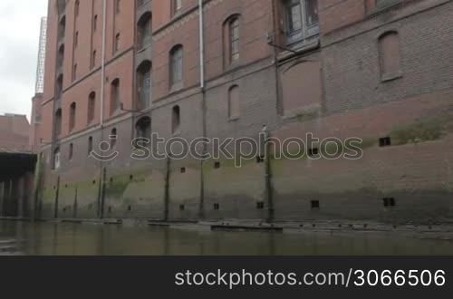 Sail along the red-brown old brick wall on the Elbe river in Hamburg.