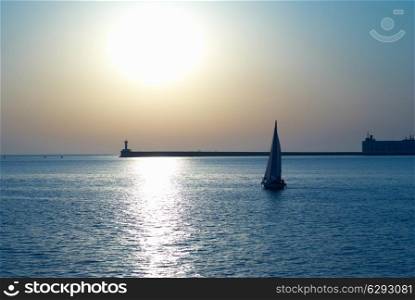 Sail boat against sea sunset. Blue marine landscape.