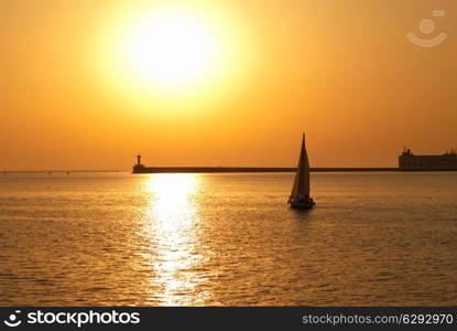 Sail boat against sea sunset. Colorful marine landscape.