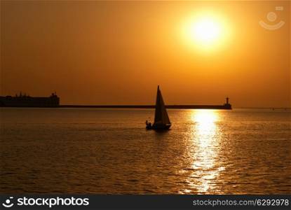 Sail boat against sea sunset. Colorful marine landscape.